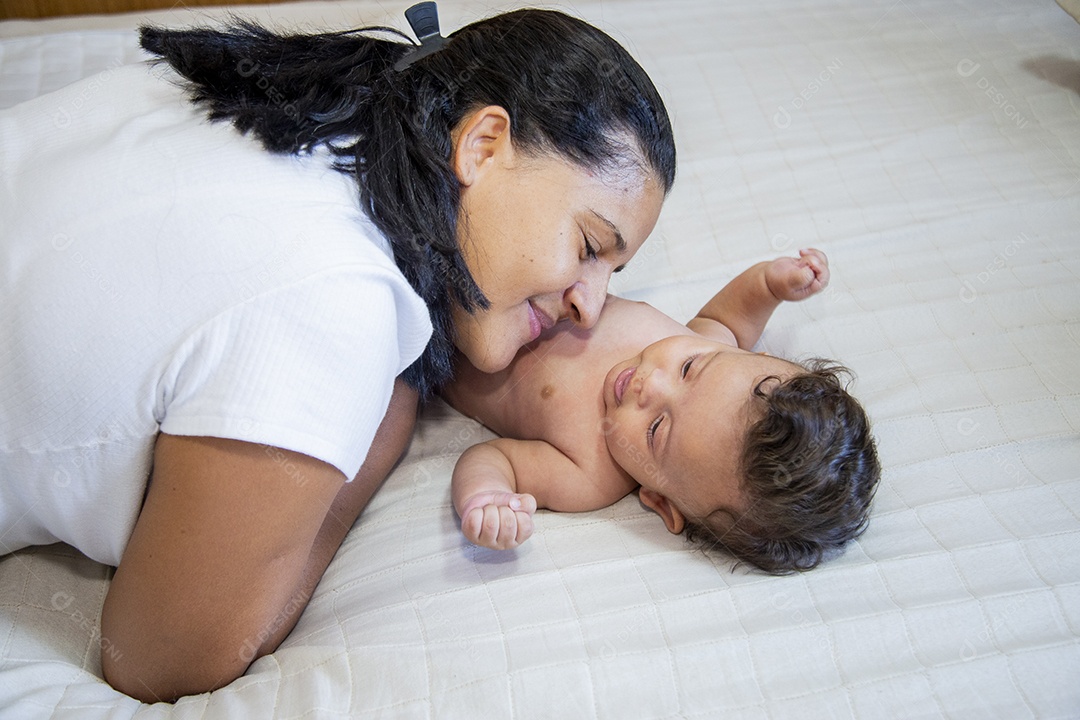 Mãe jovem cuidadando de seu filho sobre quarto