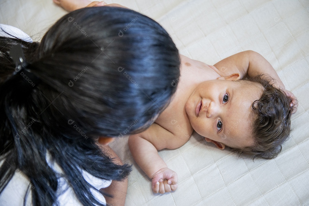 Mãe jovem cuidadando de seu filho sobre quarto