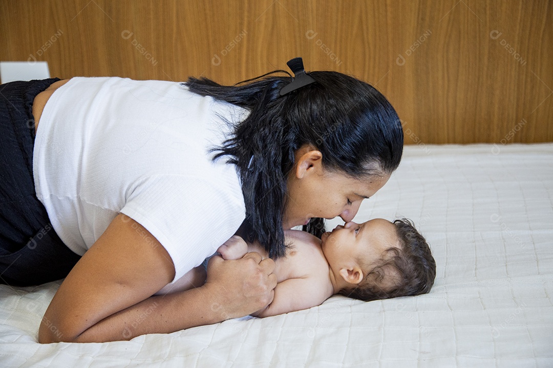Mãe jovem cuidadando de seu filho sobre quarto