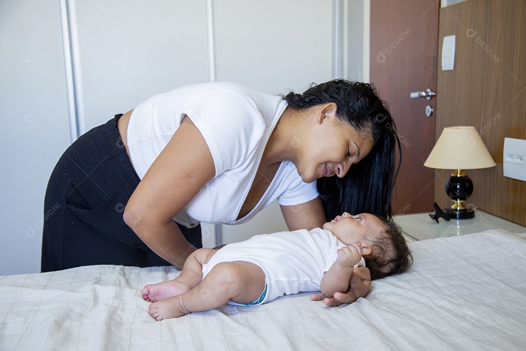 Mãe jovem cuidadando de seu filho sobre quarto