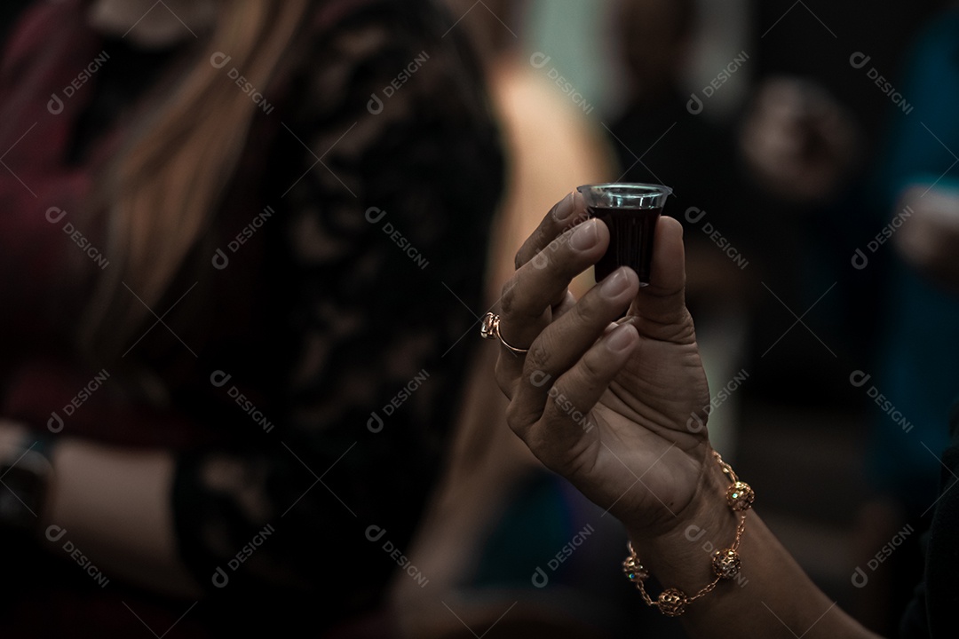 Uma mão feminina com copo de vinho para ceia