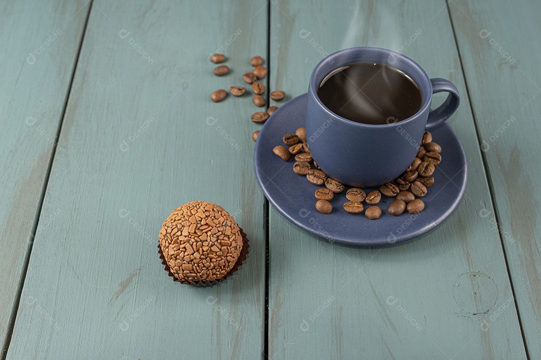 Brigadeiro com cafe e grãos sobre fundo de madeira azul