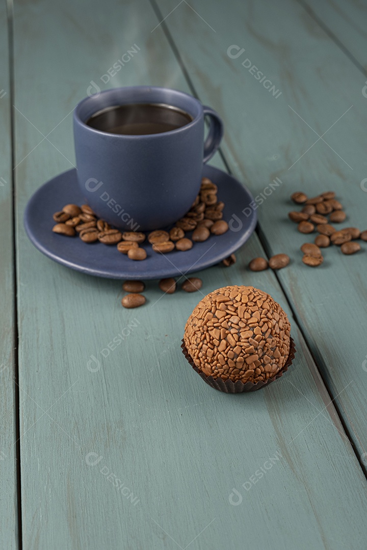 Xícara de café com grãos ao lado e brigadeiro