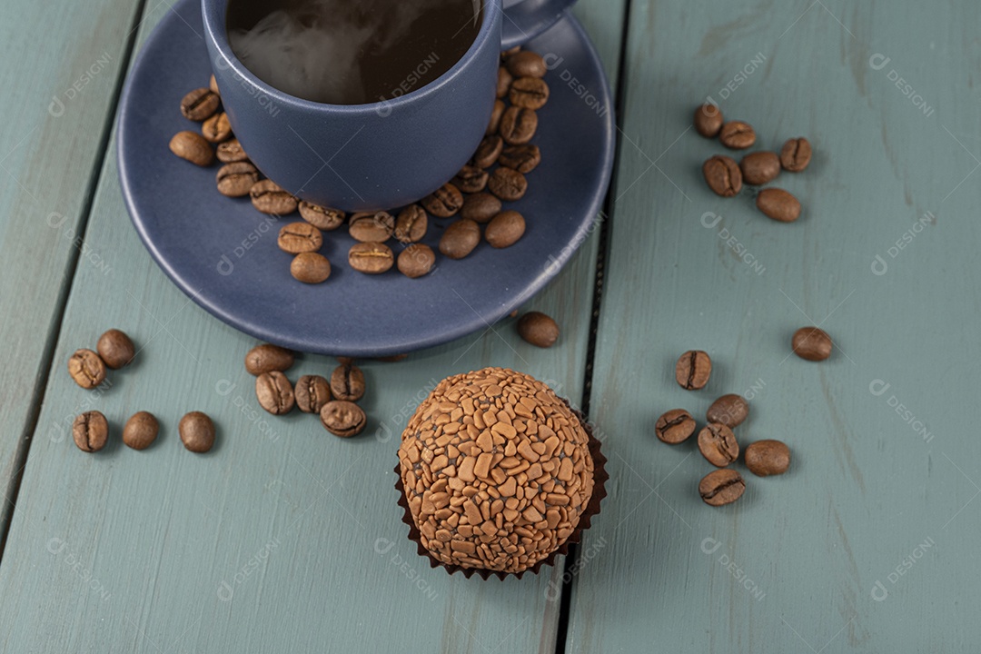 Grãos de café espalhados brigadeiro e xícara com café