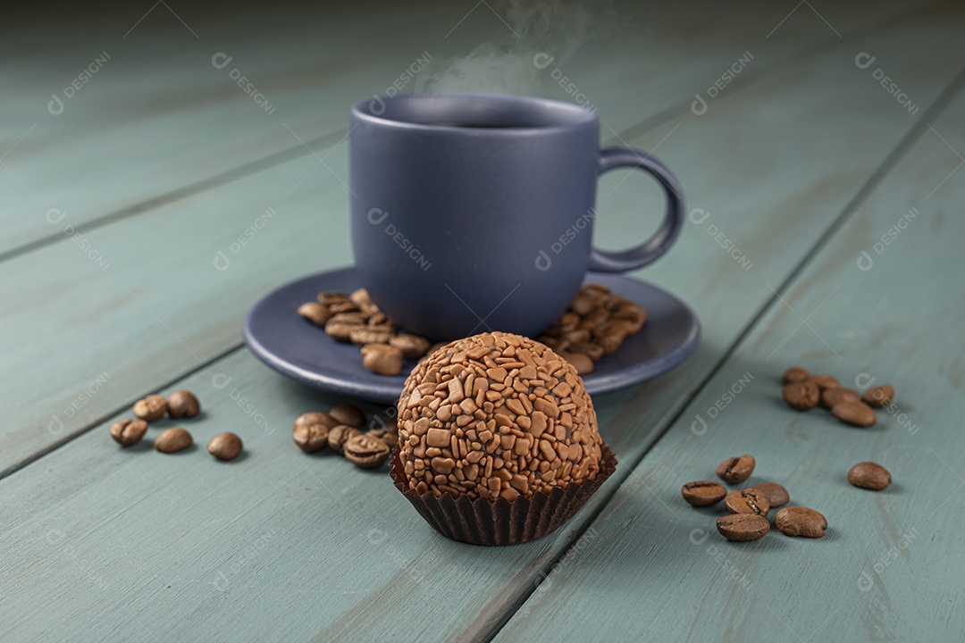 Xícara de café e grãos ao lado e brigadeiro de chocolate