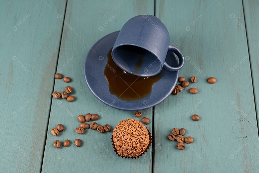 Brigadeiro com cafe e grãos sobre fundo de madeira azul