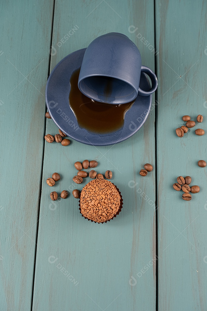 Brigadeiro com cafe e grãos sobre fundo de madeira azul