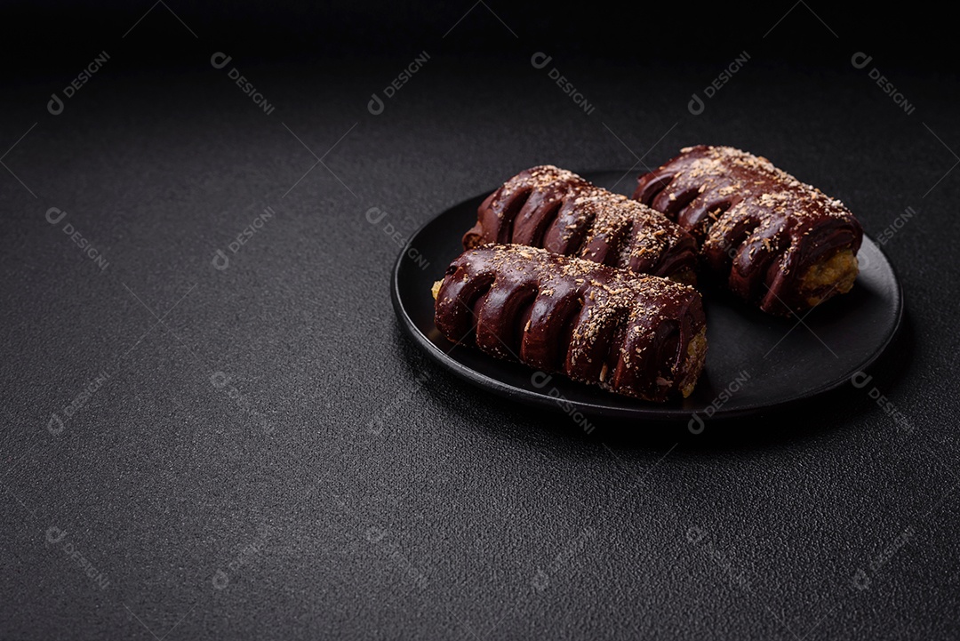 Deliciosos bolos de chocolate doce com recheio de frutas e granulados em uma placa de cerâmica sobre um fundo escuro de concreto