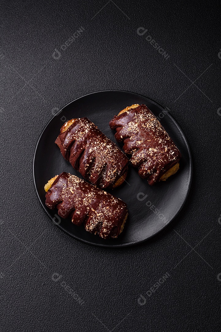 Deliciosos bolos de chocolate doce com recheio de frutas e granulados em uma placa de cerâmica sobre um fundo escuro de concreto