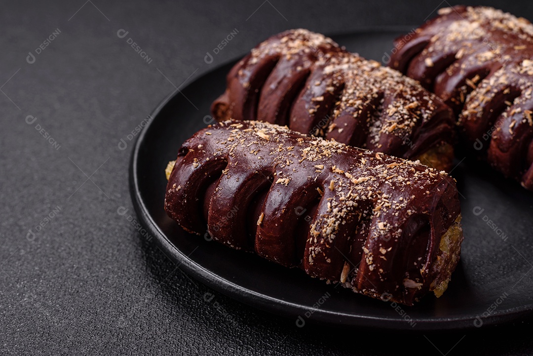 Deliciosos bolos de chocolate doce com recheio de frutas e granulados em uma placa de cerâmica sobre um fundo escuro de concreto