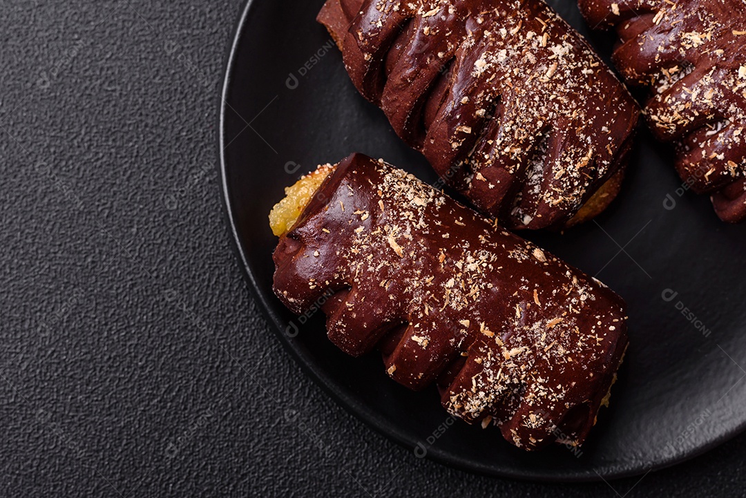 Deliciosos bolos de chocolate doce com recheio de frutas e granulados em uma placa de cerâmica sobre um fundo escuro de concreto