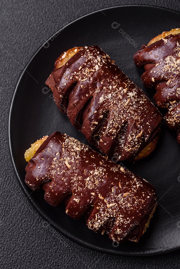 Deliciosos bolos de chocolate doce com recheio de frutas e granulados em uma placa de cerâmica sobre um fundo escuro de concreto