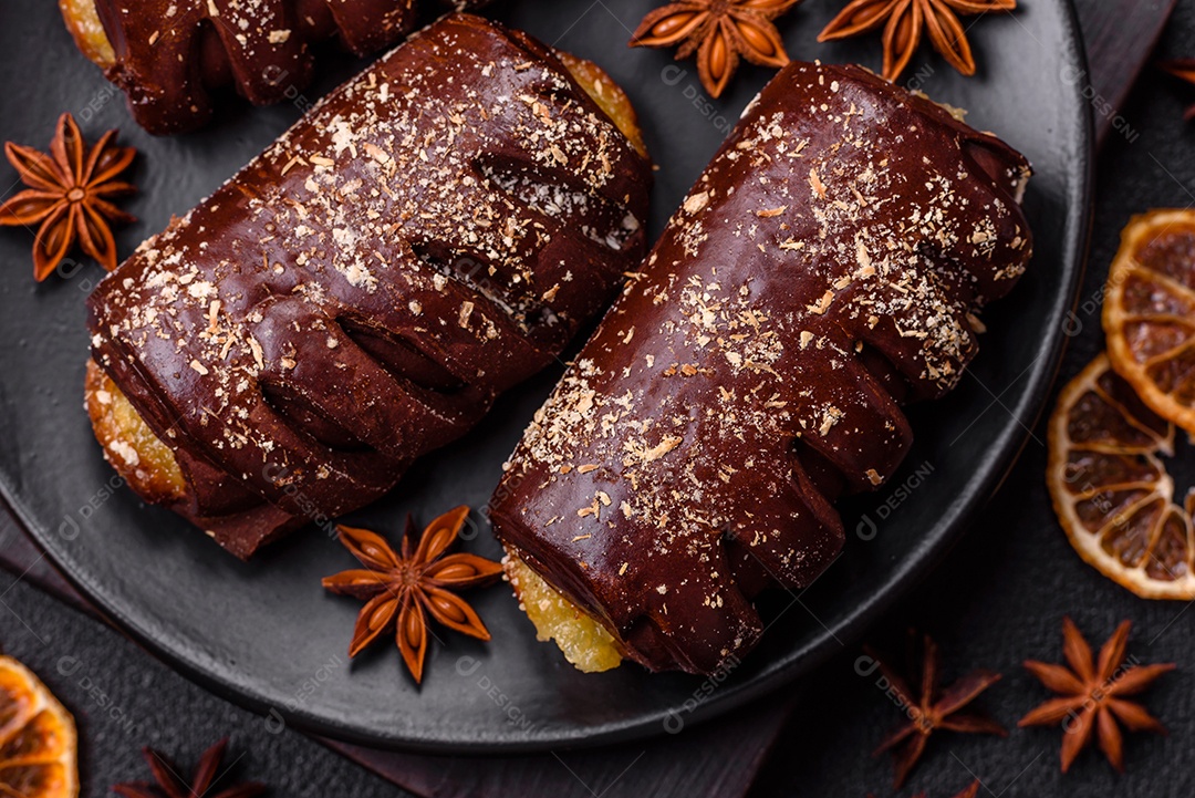 Deliciosos bolos de chocolate doce com recheio de frutas e granulados em uma placa de cerâmica sobre um fundo escuro de concreto