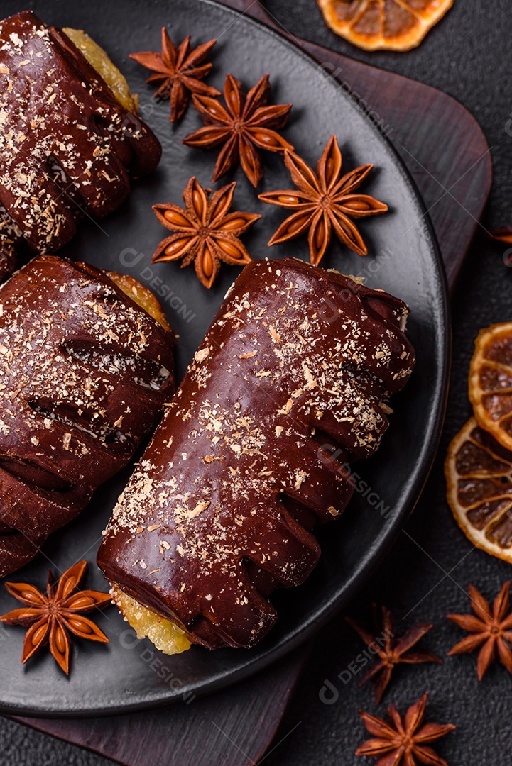 Deliciosos bolos de chocolate doce com recheio de frutas e granulados em uma placa de cerâmica sobre um fundo escuro de concreto