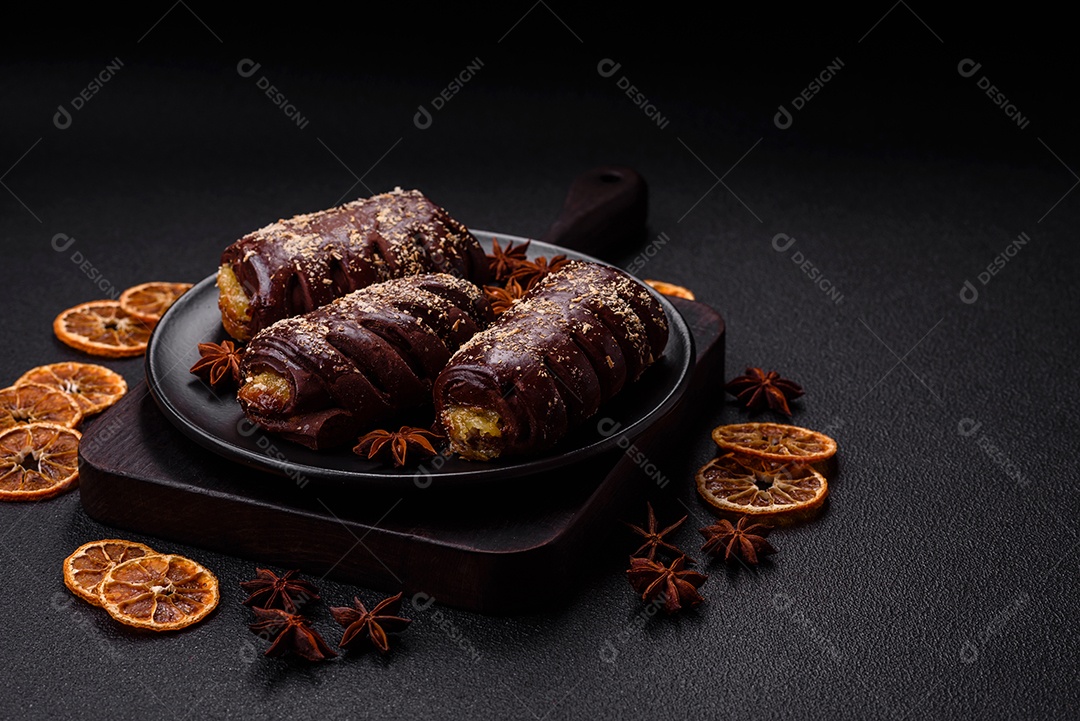 Deliciosos bolos de chocolate doce com recheio de frutas e granulados em uma placa de cerâmica sobre um fundo escuro de concreto