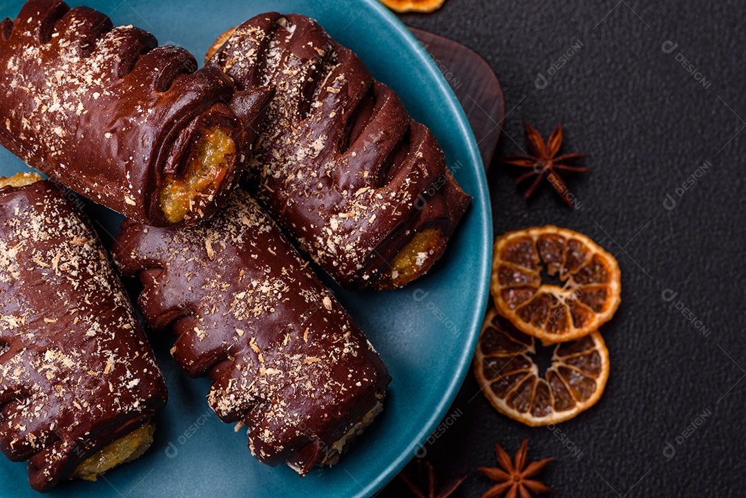 Deliciosos bolos de chocolate doce com recheio de frutas e granulados em uma placa de cerâmica sobre um fundo escuro de concreto