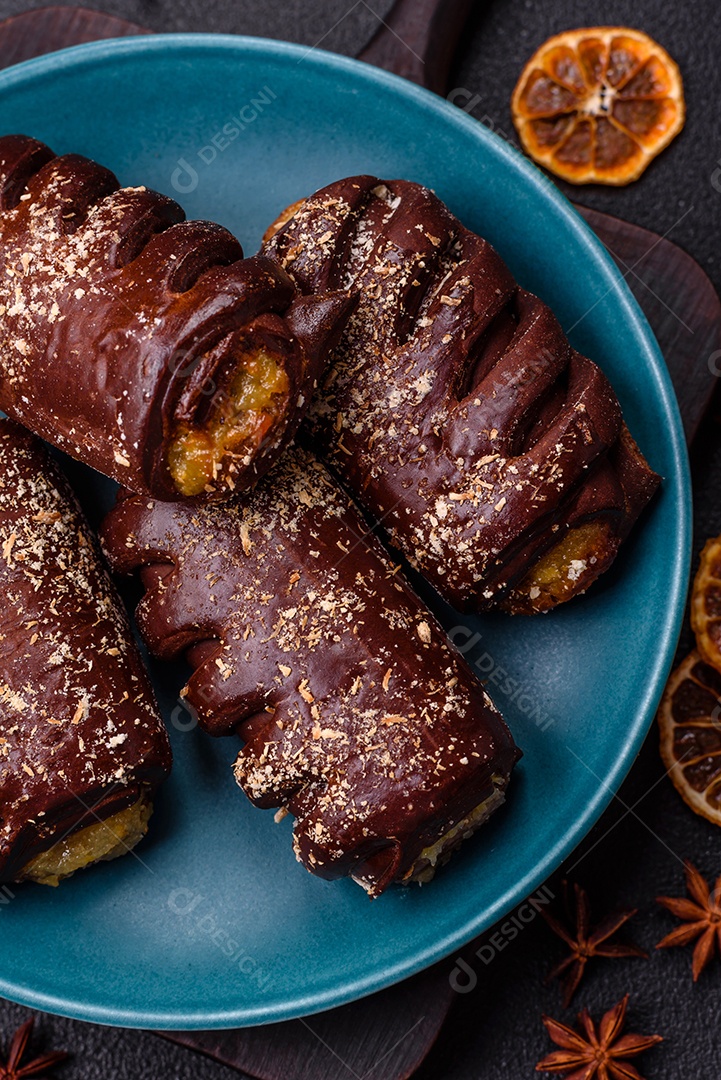 Deliciosos bolos de chocolate doce com recheio de frutas e granulados em uma placa de cerâmica sobre um fundo escuro de concreto