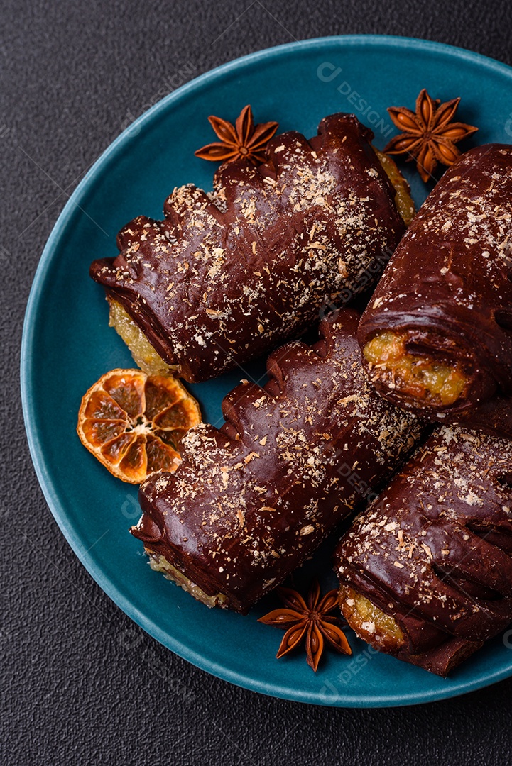 Deliciosos bolos de chocolate doce com recheio de frutas e granulados em uma placa de cerâmica sobre um fundo escuro de concreto