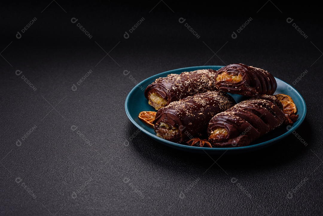 Deliciosos bolos de chocolate doce com recheio de frutas e granulados em uma placa de cerâmica sobre um fundo escuro de concreto