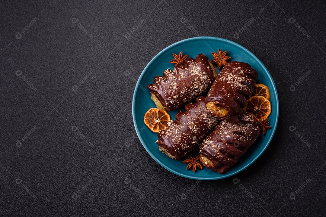 Deliciosos bolos de chocolate doce com recheio de frutas e granulados em uma placa de cerâmica sobre um fundo escuro de concreto