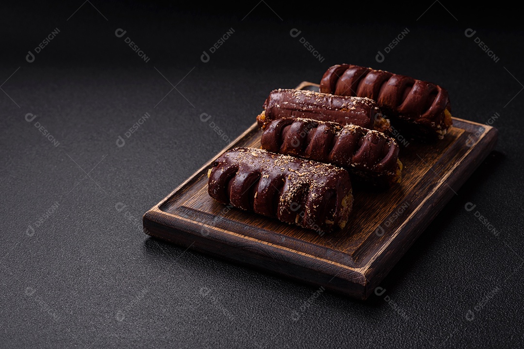 Deliciosos bolos de chocolate doce com recheio de frutas e granulados em uma placa de cerâmica sobre um fundo escuro de concreto