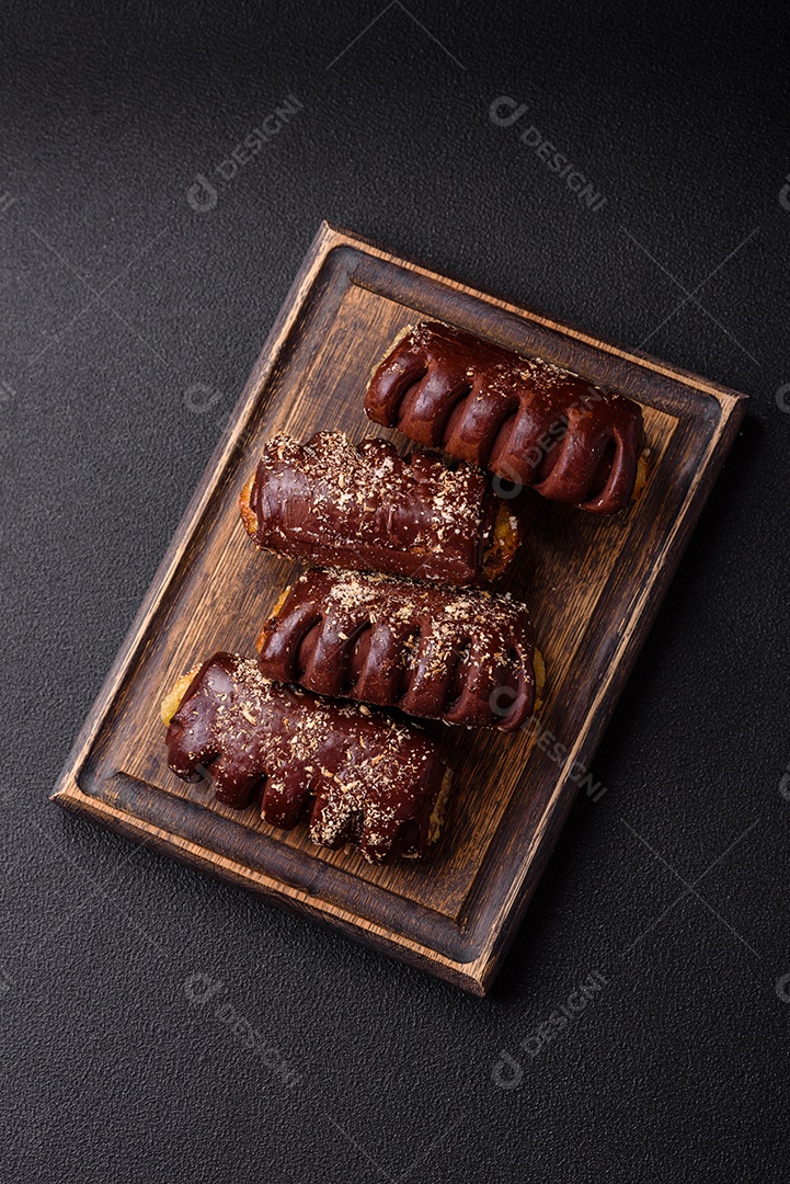 Deliciosos bolos de chocolate doce com recheio de frutas e granulados em uma placa de cerâmica sobre um fundo escuro de concreto