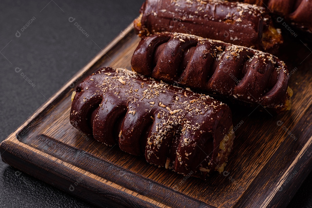 Deliciosos bolos de chocolate doce com recheio de frutas e granulados em uma placa de cerâmica sobre um fundo escuro de concreto