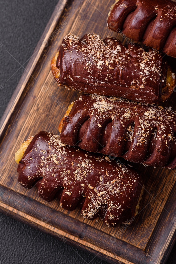Deliciosos bolos de chocolate doce com recheio de frutas e granulados em uma placa de cerâmica sobre um fundo escuro de concreto