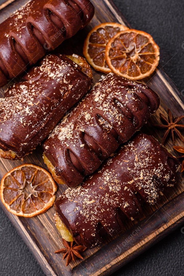 Deliciosos bolos de chocolate doce com recheio de frutas e granulados em uma placa de cerâmica sobre um fundo escuro de concreto