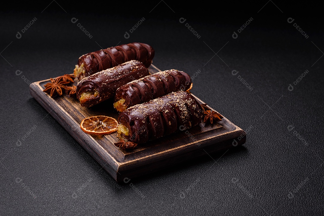 Deliciosos bolos de chocolate doce com recheio de frutas e granulados em uma placa de cerâmica sobre um fundo escuro de concreto