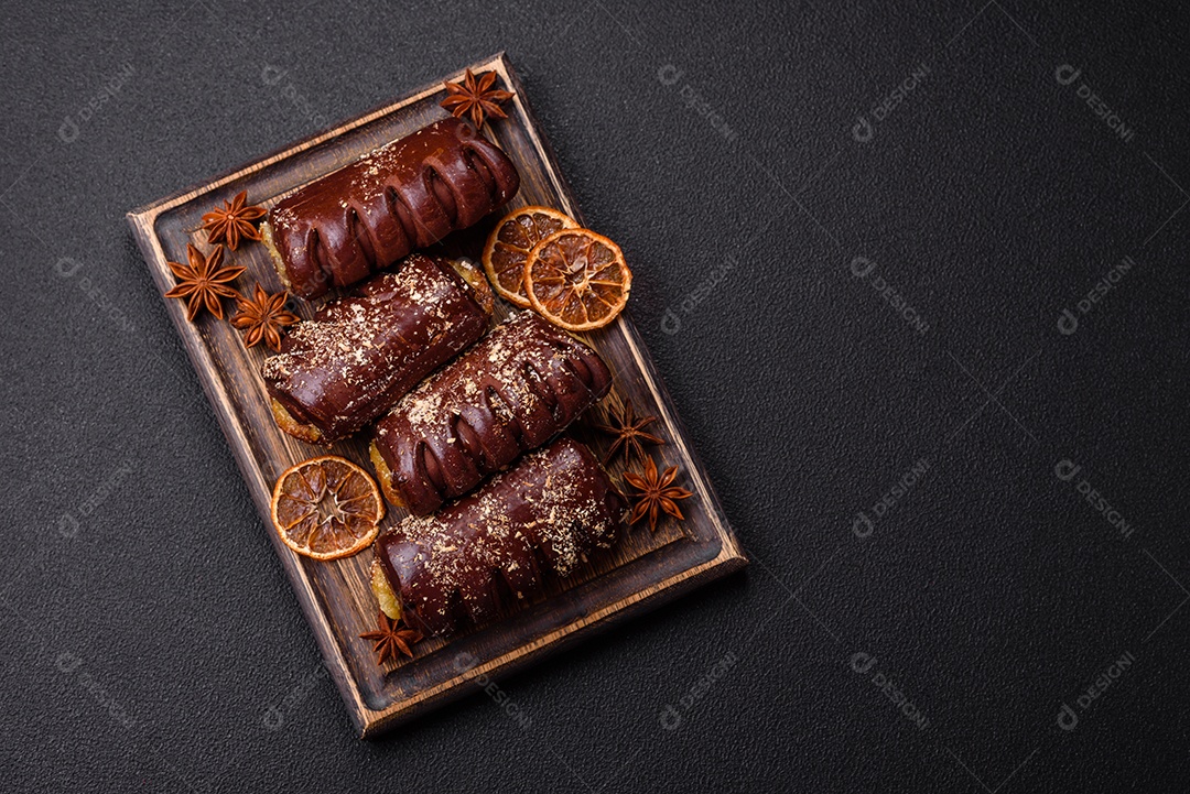 Deliciosos bolos de chocolate doce com recheio de frutas e granulados em uma placa de cerâmica sobre um fundo escuro de concreto