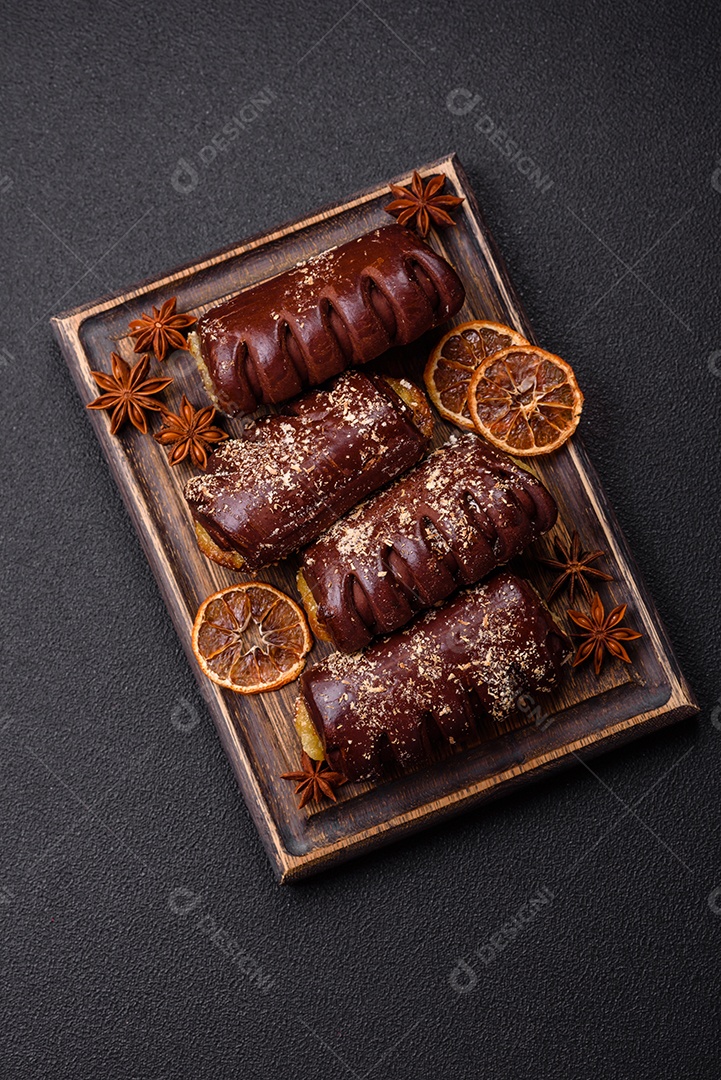 Deliciosos bolos de chocolate doce com recheio de frutas e granulados em uma placa de cerâmica sobre um fundo escuro de concreto