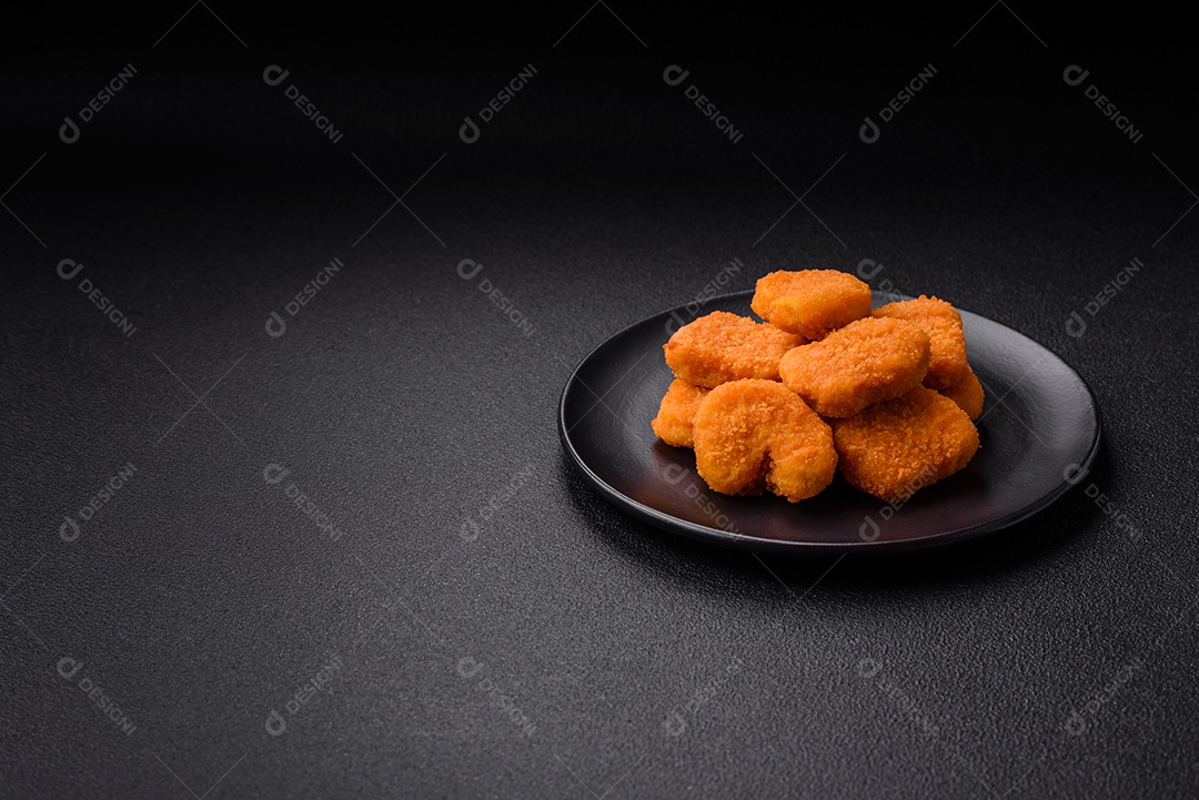 Deliciosos nuggets de frango crocantes frescos em um fundo escuro de concreto. Alimentos não saudáveis, fast food