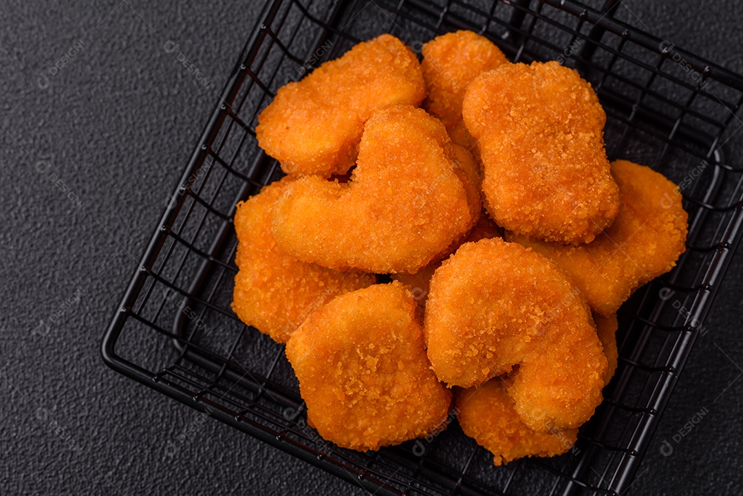 Deliciosos nuggets de frango crocantes frescos em um fundo escuro de concreto. Alimentos não saudáveis, fast food