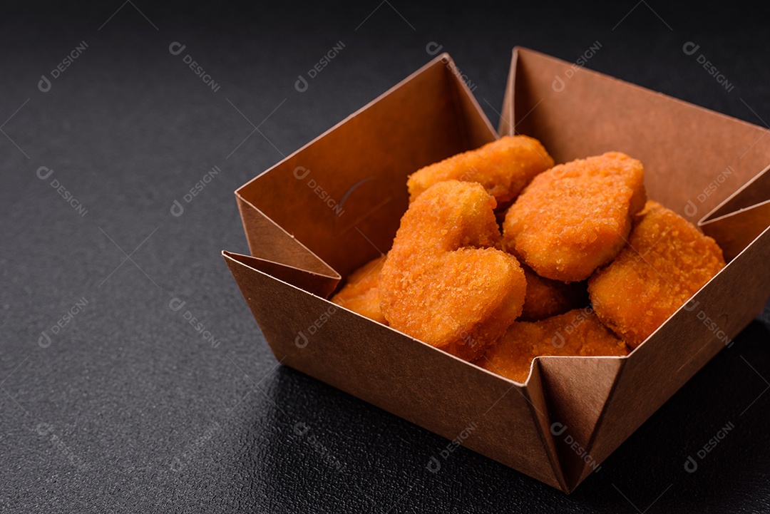 Deliciosos nuggets de frango crocantes frescos em um fundo escuro de concreto. Alimentos não saudáveis, fast food