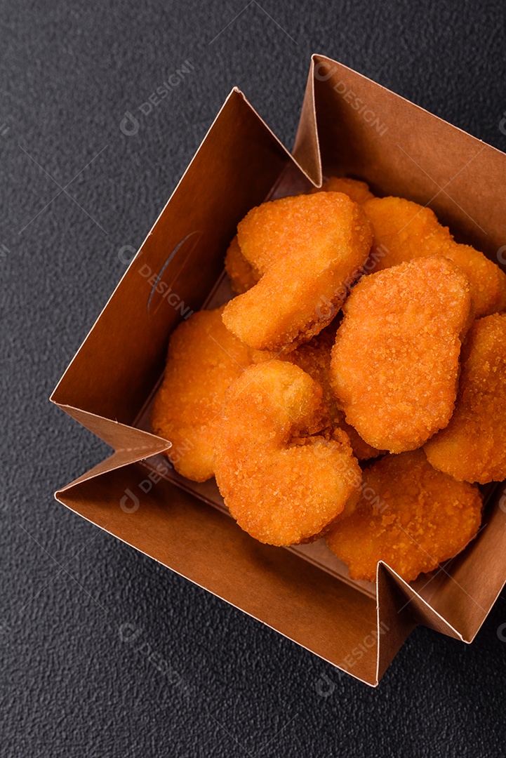 Deliciosos nuggets de frango crocantes frescos em um fundo escuro de concreto. Alimentos não saudáveis, fast food