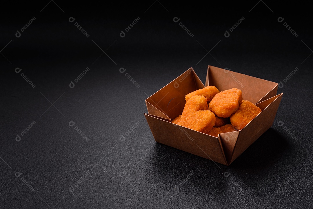 Deliciosos nuggets de frango crocantes frescos em um fundo escuro de concreto. Alimentos não saudáveis, fast food