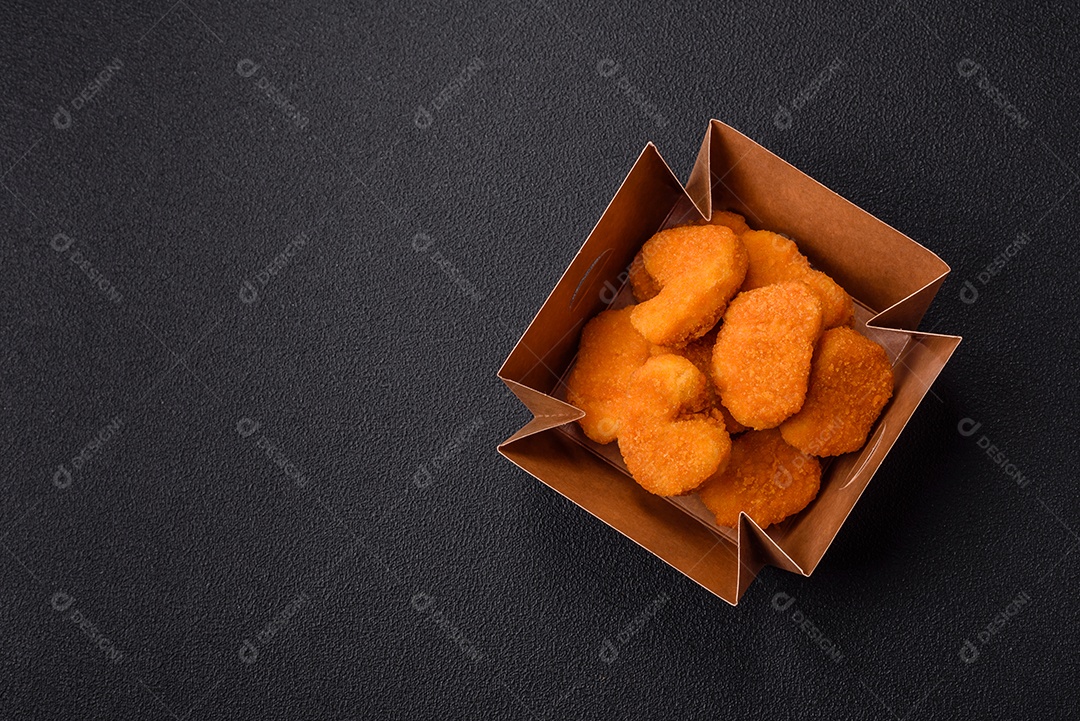 Deliciosos nuggets de frango crocantes frescos em um fundo escuro de concreto. Alimentos não saudáveis, fast food