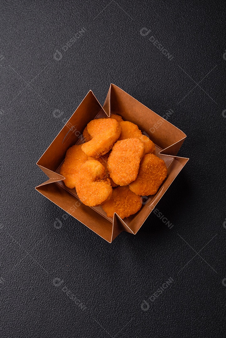 Deliciosos nuggets de frango crocantes frescos em um fundo escuro de concreto. Alimentos não saudáveis, fast food