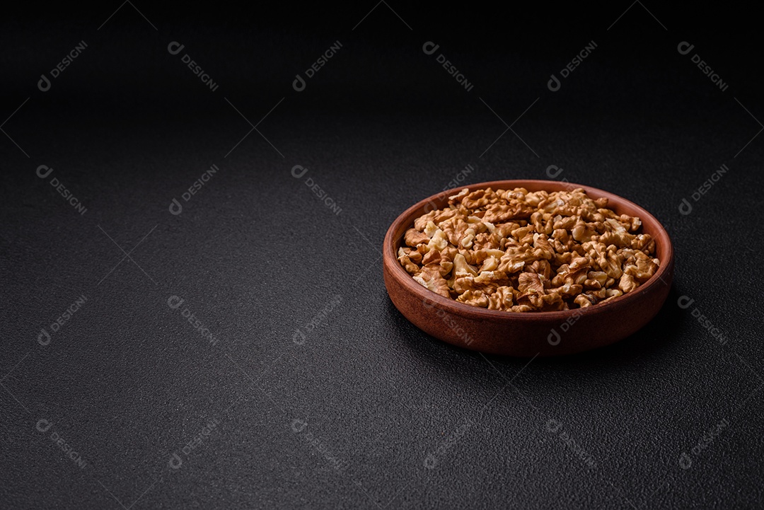 Deliciosas nozes cruas descascadas frescas em uma placa cerâmica sobre um fundo escuro de concreto