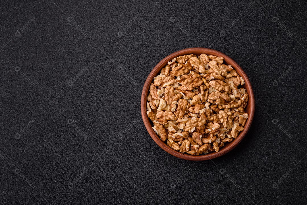 Deliciosas nozes cruas descascadas frescas em uma placa cerâmica sobre um fundo escuro de concreto