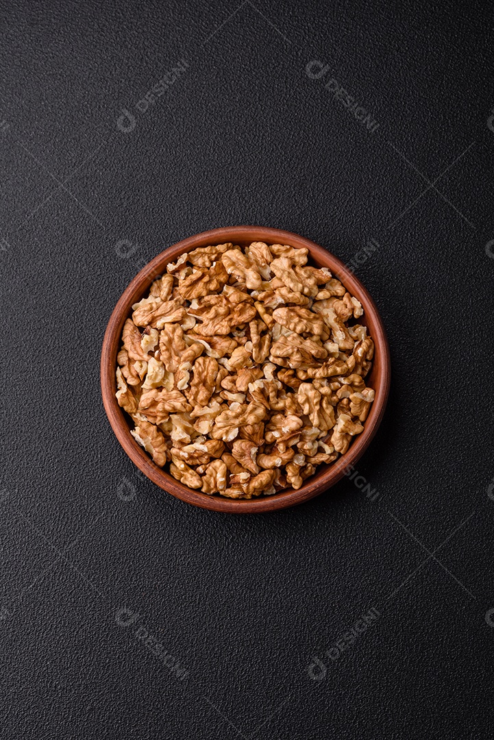 Deliciosas nozes cruas descascadas frescas em uma placa cerâmica sobre um fundo escuro de concreto