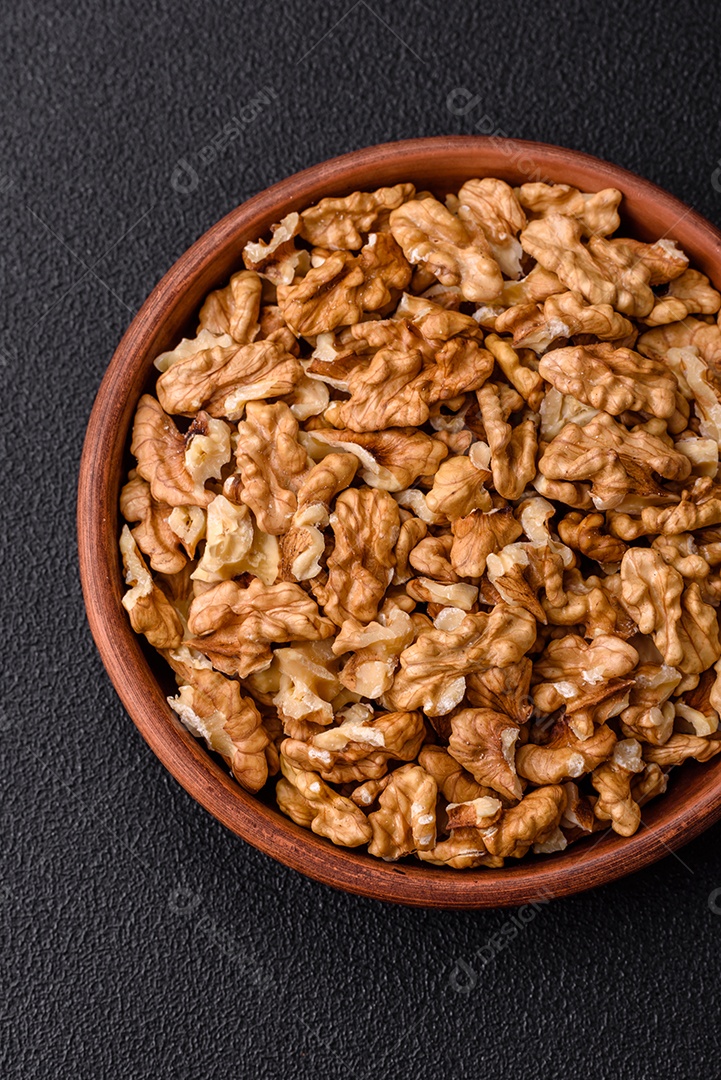 Deliciosas nozes cruas descascadas frescas em uma placa cerâmica sobre um fundo escuro de concreto