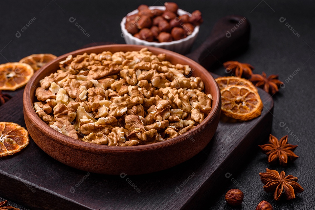 Deliciosas nozes cruas descascadas frescas em uma placa cerâmica sobre um fundo escuro de concreto