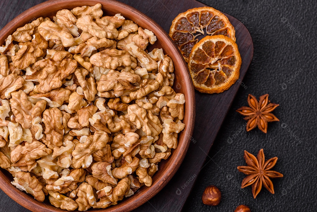 Deliciosas nozes cruas descascadas frescas em uma placa cerâmica sobre um fundo escuro de concreto