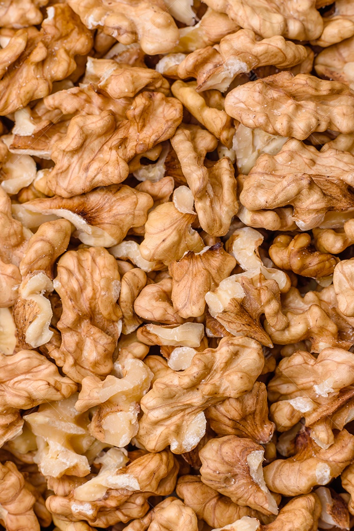 Deliciosas nozes cruas descascadas frescas em uma placa cerâmica sobre um fundo escuro de concreto