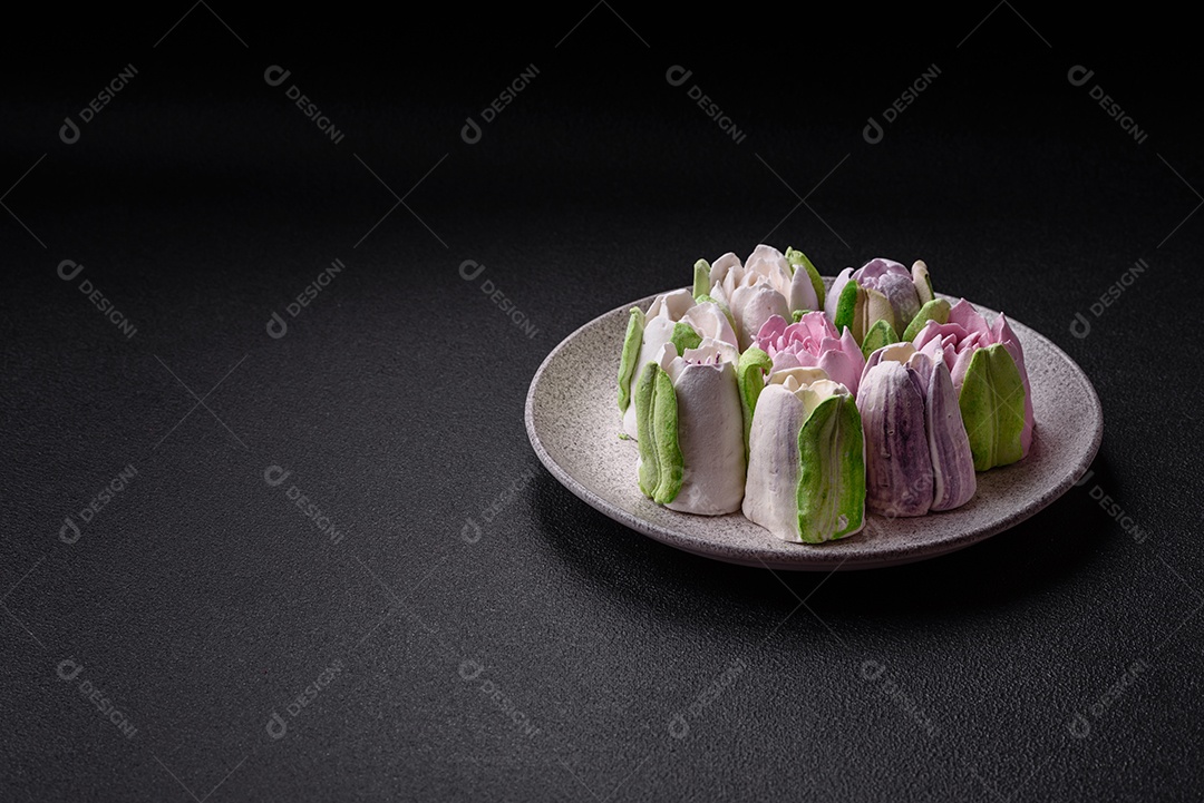 Lindos e saborosos marshmallows em forma de botões de tulipa sobre um fundo escuro de concreto