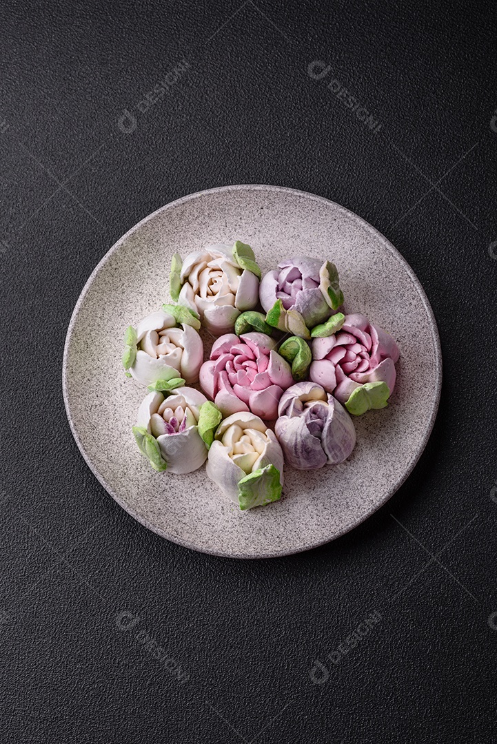 Lindos e saborosos marshmallows em forma de botões de tulipa sobre um fundo escuro de concreto