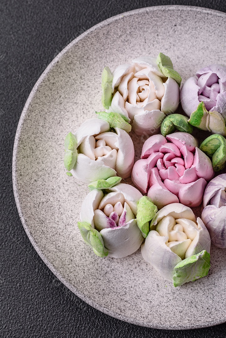 Lindos e saborosos marshmallows em forma de botões de tulipa sobre um fundo escuro de concreto