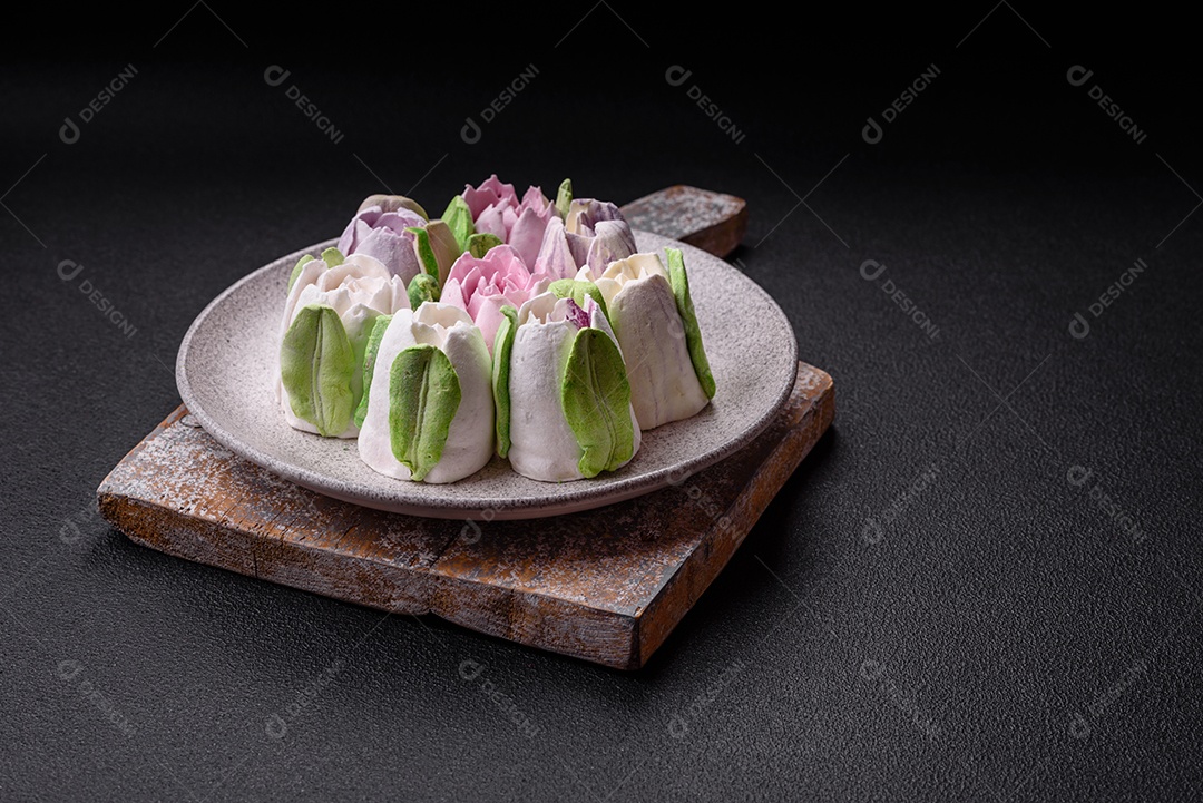 Lindos e saborosos marshmallows em forma de botões de tulipa sobre um fundo escuro de concreto